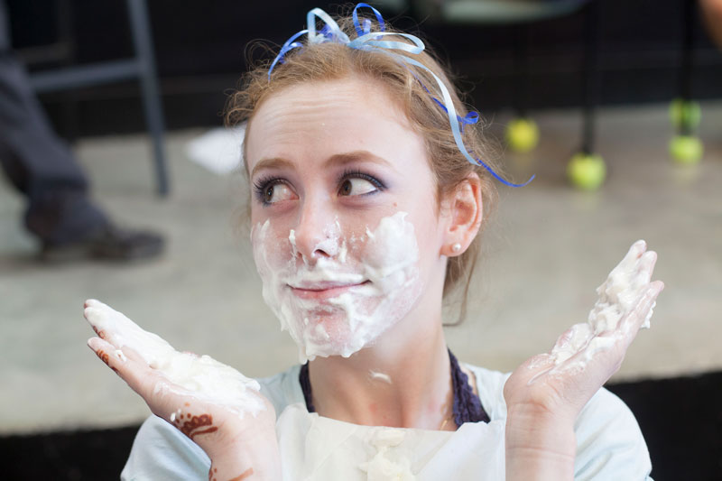 Young girl with ribbons in her hair and shaving cream smeared on her face and hands